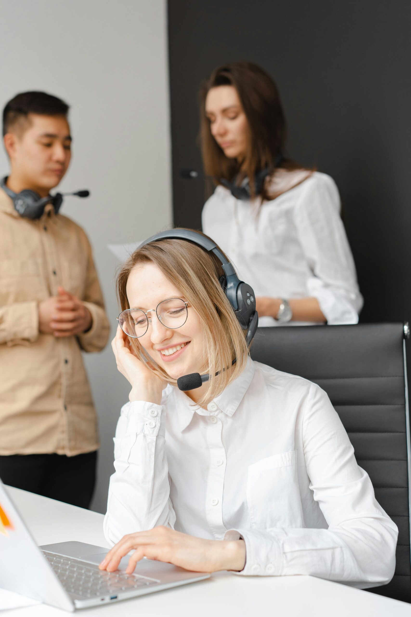 Customer service team working together in a modern call center with headsets and laptops.